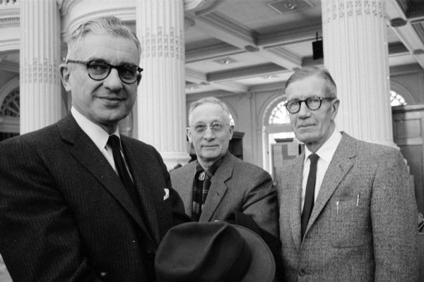 Visitors at the formal opening of the Wisconsin State Historical Society's National Mass Communications History Center. From left to right are Walter Frautschi, Melvil O. Tuhus, and Elwood R. McIntyre. They are standing on the third floor landing that opens onto the library.