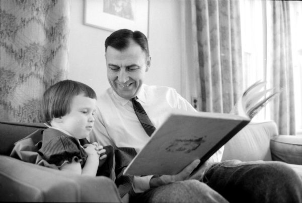 Attorney James E. Doyle, Sr. looking at a big picture book with his young daughter, Anne.