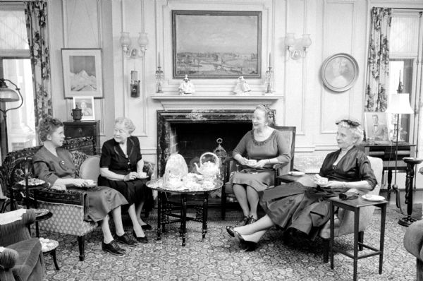 Sitting in front of the fireplace in the family home at 535 Wisconsin Avenue are Mrs. Lucien (Mary) Hanks, her daughter and two friends. They are (left to right): daughter, Sybil; Mary Hank; Elsie Moore, and Mrs. Thomas Priesley. A silver tea set on a small table is standing between them in the living room. The tea service has been used daily by the family for nearly 70 years.    

The photograph accompanies a newspaper article about the custom of serving tea daily at 4:00 pm every day with family and friends dropping in.