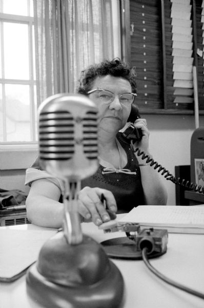 Kitty Daly, a cab dispatcher for the City Car Co. for the past 17 years, has been answering the phone in front of a microphone and an electrical telegraph. She is the first woman dispatcher for the company.