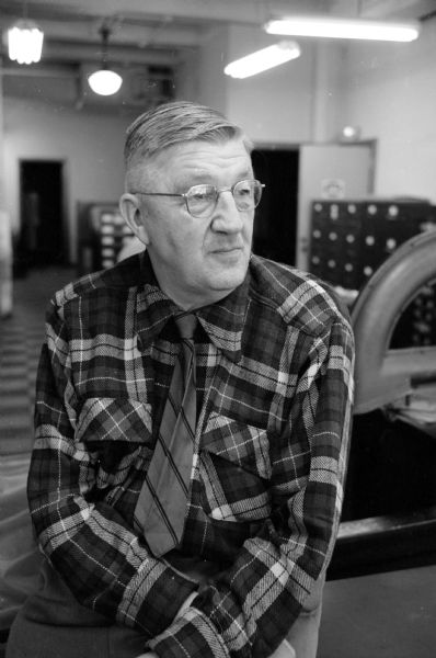 Portrait of Arthur Vinje, veteran <i>Wisconsin State Journal</i> photographer, taken before the 43rd annual high school boys basketball tournament. He is wearing a plaid shirt and a striped tie.