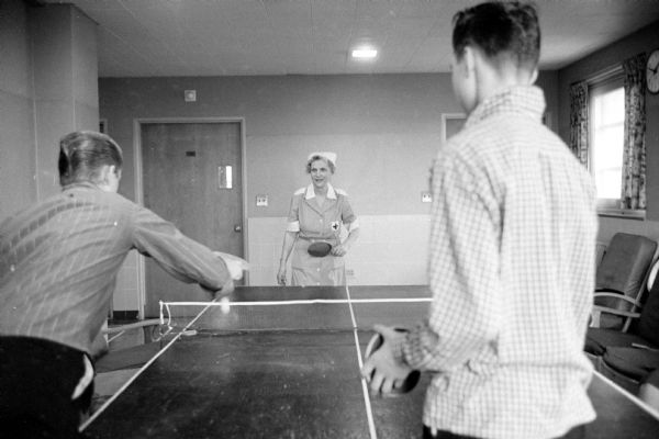 Red Cross Gray Lady Mrs. Robert A. Judd (1115 Edgehill Drive) playing ping-pong with two teenage boy patients at the Wisconsin Diagnostic Center at 1552 University Avenue. Mrs. Judd volunteers many hours of her time to being a friend to the children at the center.

The center was under the supervision of the Mental Hygiene Division of the State Department of Public Welfare and connected with the University of Wisconsin Medical School as a training ground for medical students and future psychiatrists.