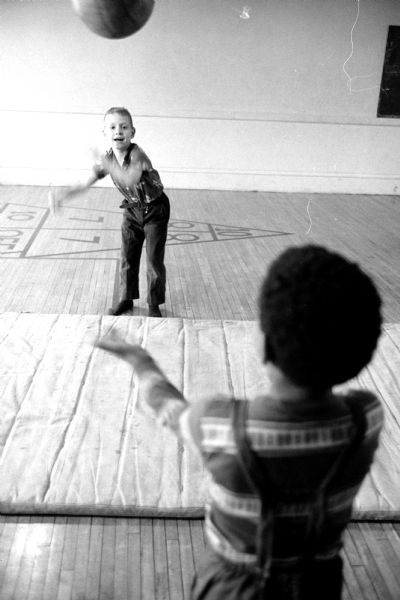 Bobby Abbott (background, 22 South Park Street) and Ernest Vance (4 South Francis Street) are playing catch in a gymnasium at the Neighborhood House at 768 West Washington Avenue. They are members of the first-grade boys' group at the center. Sam S. Fried (955 Lake Court) is director of the center.