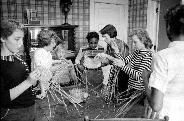 A favorite activity for the 11- and 12-year-old-girls group at the Neighborhood House at 768 West Washington Avenue is basket weaving.
Mrs. Wendall V. Harris (1430 Mound Street), assistant director of the center, is shown supervising the group.
Shown (left to right) are: Kay Vanderbilt (404 South Park Street); Roxie Anderson (701 Milton Street); Barbara Germann (1026 College Court); Barbara Vance (424 Mound Court); and Frances Cardarella (820 Milton Street).   