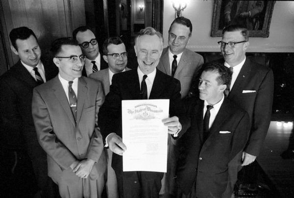 Governor Vernon W. Thomson proclaims National Want Ad Week in Wisconsin. The week is sponsored by The Association of Newspaper Classified Advertising Managers. Gov. Thomson is shown with classified advertising managers from Wisconsin newspapers.
They are: (back row) Melvin Parsons, Appleton Post-Crescent; Eldred R. Garter, 4337 Travis Terrace, Madison Newspapers; L. A. Pierson, Beloit Daily News; and Ray Kruck, Manitowoc Herald-Times;
(front row) Joseph Novak, Janesville Gazette; William Johnston, Jr., Watertown Times; Gov. Thomson; and H. O. Goodchild, Green Bay Press Gazette.     