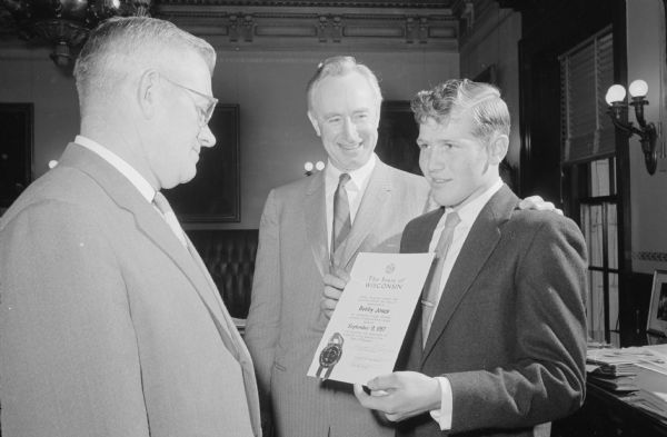 Bobby Jones (Arena) is receiving an award for his life-saving efforts in the Governor's Office on March 18th, 1958. Bobby is showing his father the award and standing next to Governor Thomson.

On September 9, 1957, four persons, including school child Janet Linley, were injured when two cars collided with an Arena school bus on Highway 14. Other pupils escaped injury when Bobby Jones, an older pupil, prevented them from going into the roadway.