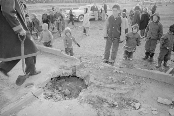 Young children inspect the hole where Patricia Ann Palmer's (2) leg was caught in an unused drainage pipe at Truax Park. Rescue workers cut the hole in the concrete foundation of an Army barracks where the 4-inch pipe trapped young Patricia Ann's right leg.   