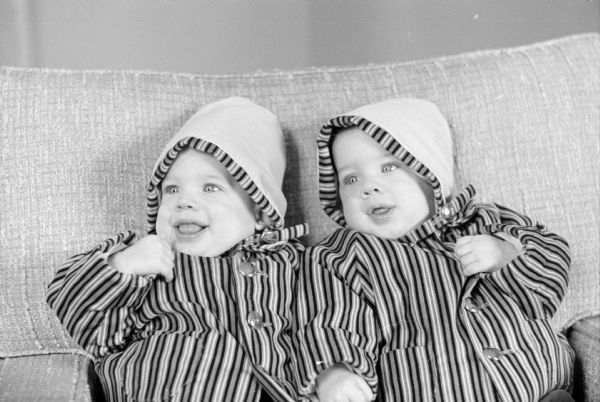 Six-month-old twins Matthew and Michael Baer, sons of Mr. and Mrs. Neil Baer, are shown wearing striped sports jackets and beige caps with matching trim as their Easter bonnets. They are the grandsons of Ray Baer and Mr. & Mrs. Don McNearney.