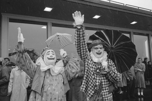 Shriner clowns Harley Moore, left, and Ray Wheeler waving goodbye to the Zor Shrine group leaving the Madison airport for a tour of Hawaii.