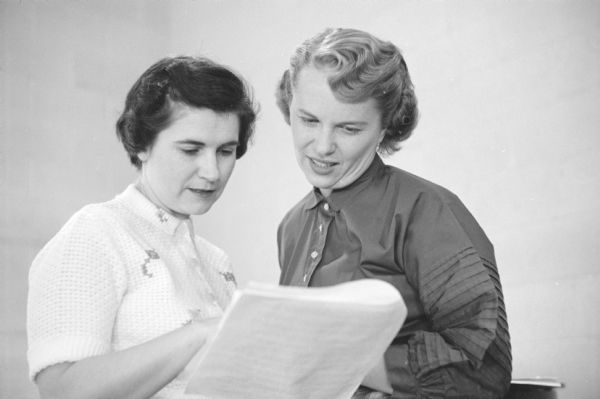 Two women examine a script. Jeanne Anderson, left, was chairman of the children's style show sponsored by the East Side Women's Club and held at the East Side Business Men's Club House. She is discussing the script with Janice Foss, the narrator.