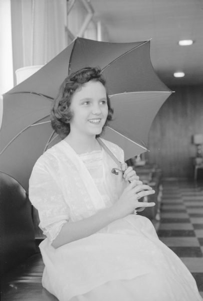 Jullaine Simon holds an umbrella while modeling a 1913 confirmation dress at the Children's Style Show sponsored by the East Side Women's Club.