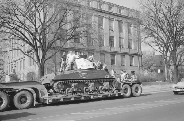 Delta Sigma Pi fraternity members and friends ride the 33-ton used Sherman tank that the fraternity purchased from the Army at Camp McCoy, from the Milwaukee Road depot to Ed's Service Station, 1443 University Avenue, where it was on display until Armed Services Day, when it was moved to the fraternity for a spring "Tank Party". Later, the tank was donated to a veterans' group for use as a war memorial.