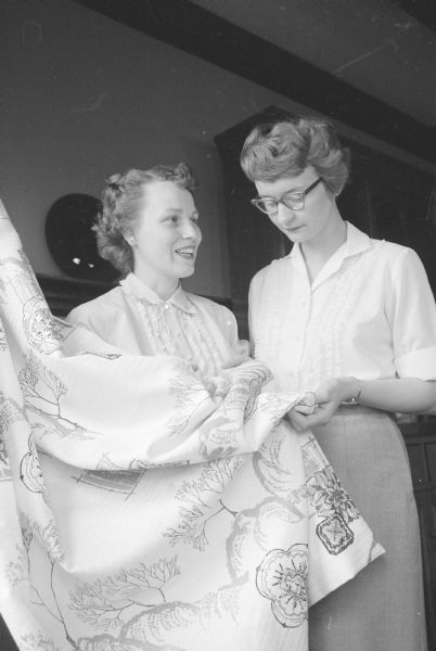 Kathleen Russell, right, Iowa County home agent, with Mrs. John Harrison looking at draperies made by her for her new home.   