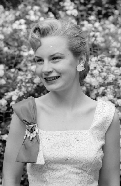 Portrait of Diane Barber, a U.W. student, with rose bushes in the background. She was named as queen of the annual rose show of the Madison Rose Society.  