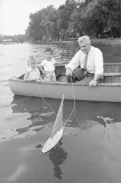 Grandfather Henry Reynolds, Route 1, Waunakee, spends time "sailing" with his grandchildren Janet (4 1/2) and Jeffrey (2) on Lake Mendota.
Their parents are Mr. and Mrs. John B. Coatta, 616 W. Mifflin Street. Mr. Coatta was a star quarterback for the U.W. football team in 1949-1951 and later the U.W. head football coach.   