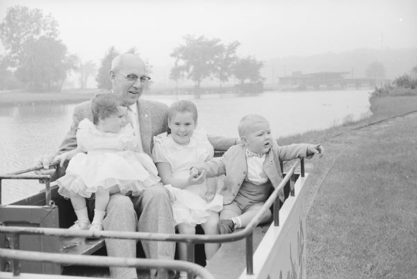 Grandfather L. J. Padgham, Schroeder Road, spends time at Vilas Park with his grandchildren (L-R) Jody (2) and Patti (4 1/2), daughters of Mr. and Mrs. Jack Padgham, 21 Kewaunee Court; and Jimmy (2), son of Mr. and Mrs. Gerald Padgham, 131 S. Marquette Street.      