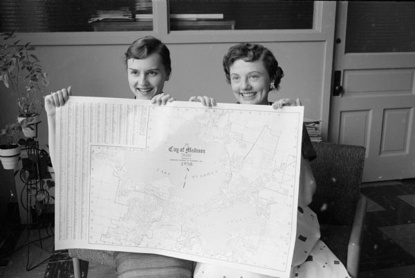 Two Madison Chamber of Commerce employees are shown holding the newest map of the city printed by the chamber. The maps sold for ten cents.  The two women are Gail Johnson and Dorothy Taylor.   