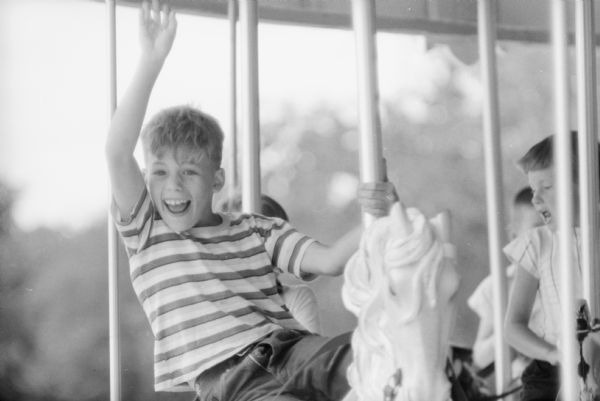 An unidentified boy enjoying his first ride on the new Vilas Park merry-go-round during the merry-go-round's grand opening. 