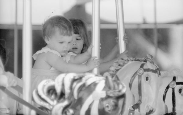Two young girls having their first ride on the new merry-go-round at Vilas Park. The grand opening for the merry-go-round was held on June 21, 1958.  