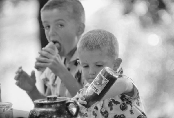 Brothers Jim and Pat enjoying hot dogs during a family picnic in the backyard of the Professor Frank J. Remington home.