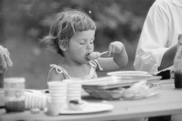 Daughter Ann enjoying the food during the Professor Frank J. Remington family picnic in their backyard.