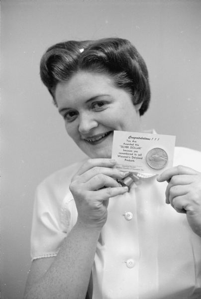 Twila Nolen, a waitress at Rohde's Steak House, is shown after receiving her second silver dollar from the Madison Chamber of Commerce. It is part of a June Dairy Month Promotion in which the dollars are given to waitresses and store clerks who suggest to customers that they purchase dairy products with meals or grocery purchases. 