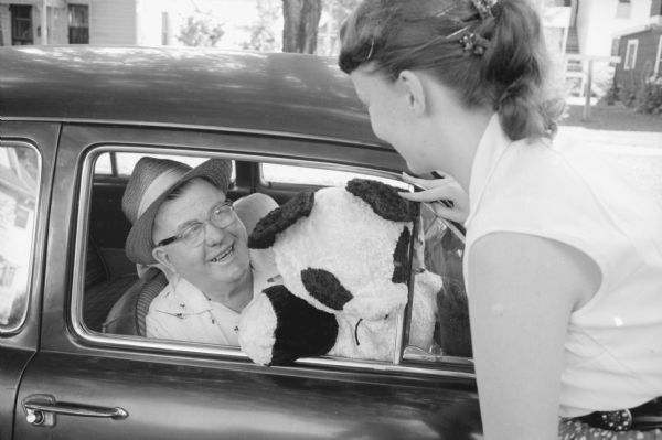 The Edgerton Pat Boone fan club's major project is to repair used toys, games, and books for the Martin Luther Children's home in Stoughton. Club president Janice Hubred's grandfather, Clarence Orvold, is shown with a stuffed toy panda in his car to deliver to the home.