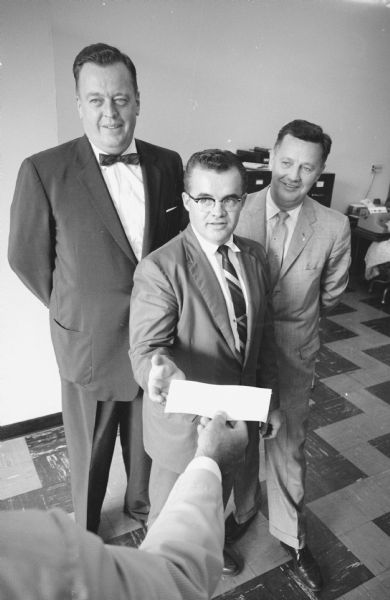 The National Sales Executive club of Madison purchased stock in the Madison Improvement Corporation. Pictured are, left to right: John G. Schutz, president of the club; club member Ned Fox; and Henry Behnke, president of MIC.