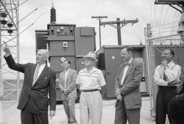 Switch-throwing ceremony for the new electric sub-station in Sun Prairie on Market Street. Five men are standing in front of the transformer and other equipment, including Anton "Tony" J. Klubertanz, chair of the Sun Prairie Water and Light Commission. The new sub-station replaces one built by the Wisconsin Power and Light Company about 1949.