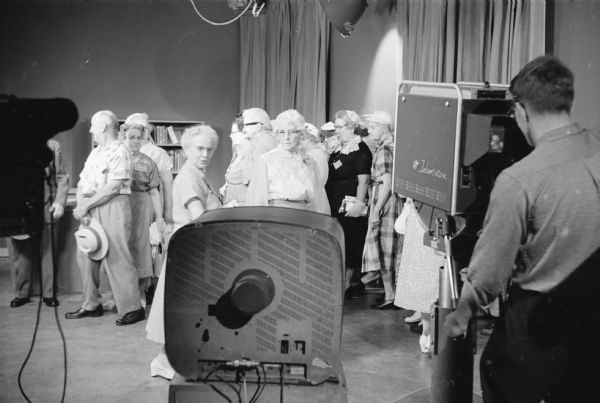 Members from Madison's five Senior Citizens groups tour the University of Wisconsin television station WHA-TV. The group reacts when they view themselves on a television for the first time.