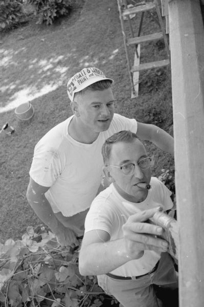 Overhead view of Norbert Anderson's friends who pitched in to help paint his home at 1522 Jefferson Street. At right, Kenneth Jones demonstrates his painting skill to James Karns.   