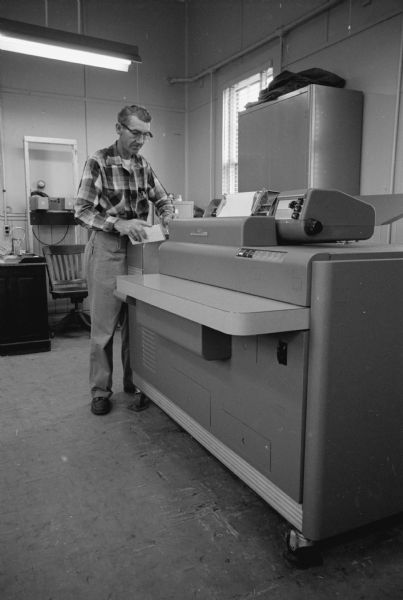 North Western railroad yard employee John Eith is shown with punch cards in hand by a new IBM "accounting apparatus". He is "awaiting information from one of the other machines as to the contents of freight cars and destinations". The information compiled by the machines is relayed directly to the railroad's Chicago headquarters.