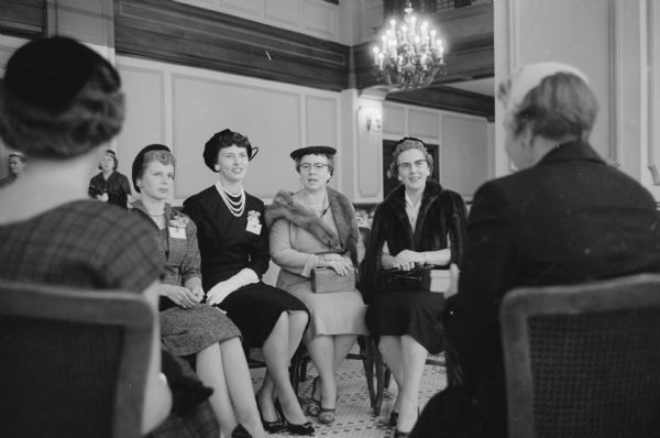 Four women attending the annual state convention of the Wisconsin Chiropractic Association Auxiliary at Hotel Loraine are: Margaret Smith, Madison; Mrs. C. S. Gonstead, Mt. Horeb; Gayle Ryden, Madison; and  Mrs. M. O. Gray, Wisconsin Dells. Two women are sitting in the foreground with their backs to the camera.