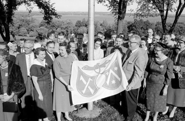 The Madison Printing club presented a flag to the Sixth District International club at the club management workshop for the Printing House Craftsmen at the Blackhawk Country club. Holding the flag at the ceremony are Roberta Froncek, left, and Harold E. Sanger, Sixth District president, Chicago.