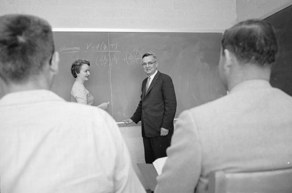 Lynn Stodola, Black River Falls, one of the few U.W. College of Engineering  chemical engineering students, stands at the blackboard with Professor Roland A. Ragatz, 4310 Cherokee Drive, in a thermo dynamics course. Stodola is the only woman in the class.
  