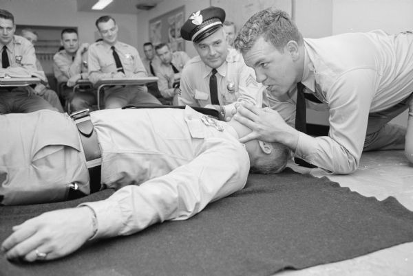 The Madison Police Department uses a training film to teach mouth-to-mouth artificial respiration. Shown during a practice session are (L-R) trainer Sgt. Fred Williams, cadet policeman William Wurtzler and "victim" Sgt. Dan Writt.  