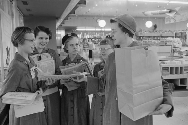 Four Girl Scouts hand out voting literature prepared by the League of Women Voters at the Red Owl store on University Avenue. Dorothy Kittleson takes a pamphlet from scouts, (left to right): Cathy Nason, Connie Larson, Pamela Krolski, and Cheryl Hobert.