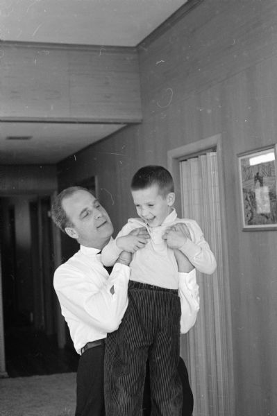 Governor-Elect Gaylord Nelson holding his son Gaylord, Jr (Happy) (5) in the family home at 5627 Crestwood Place. The photograph was taken prior to the Nelson family moving into the Governor's Mansion in Maple Bluff.  