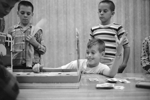 Competition during a table top basketball game played with ping-pong balls at the Van Hise School recreation center. Bob Reinfreid, son of Dr. and Mrs. William R. Reinfried, 4834 Marathon Street is shown throwing a basketball. The other two boys are not identified.