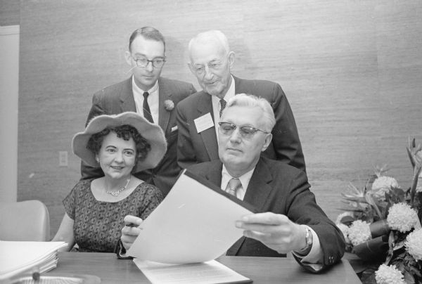 The Wisconsin Bankers Association holds an open house at their new offices in the Wisconsin Power and Light Company building, 122 W. Washington Avenue. Shown signing an association pension trust certificate is Eugene Drzycimski, president of the Lincoln State Bank of Milwaukee. Looking on (L-R), are: Mrs. Eugene Drzycimski, Milwaukee; George Bushnell, Jr., association secretary, 1443 Chandler Street; and Robert B. Wood, 1433 E. Johnson Street.     