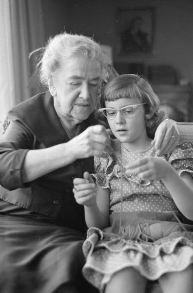 Mary B. Cowdin (Granny), Mary C. Metz and Ralph W. Metz financed and built a house at 4725 Lafayette Drive with a full apartment for Granny and the rest of the house for the Metzes and their three children. The image shows Mary B. Cowden teaching her grand daughter, 9-year-old Phyllis Metz, how to knit.