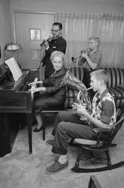 Mary B. Cowdin is in her apartment playing her piano and joined by her son-in-law, Ralf Metz, who is playing a violin, and her grandsons Scott, 12, and Allen, 15, who are each playing horns.