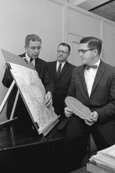 Lowell E. Frautschi, chairman of the research advisory committee of the Community Welfare Council (left), confers with Leonard Pederson of Oscar Mayer and Company and William Werner of the National Machine Accountants Association regarding a study to determine the extent of service to Madison youngsters.
