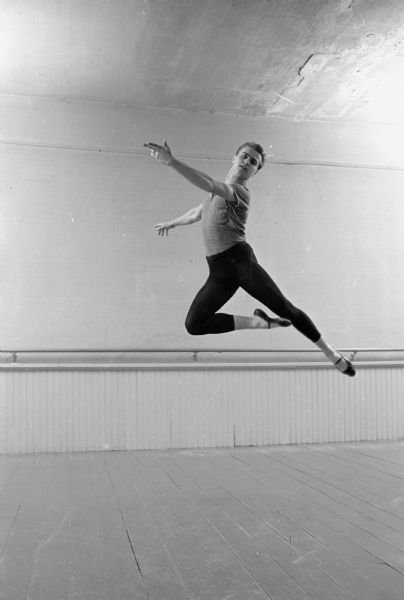 Tibor L. Zana, a 23 year old Hungarian dance instructor and student at Carroll College, teaches ballet to about 60 residents of Lake Mills in a room over a garage in the city. Zana came to the United States on February 15, 1957 to live with his uncle in Washington, D.C. He is shown performing a classic ballet movement during a break between classes.    
