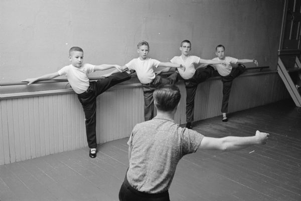 Tibor L. Zana, a 23 year old Hungarian dance instructor and student at Carroll College, teaches ballet to about 60 residents of Lake Mills in a room over a garage in the city. Zana is shown instructing a boy's ballet class.