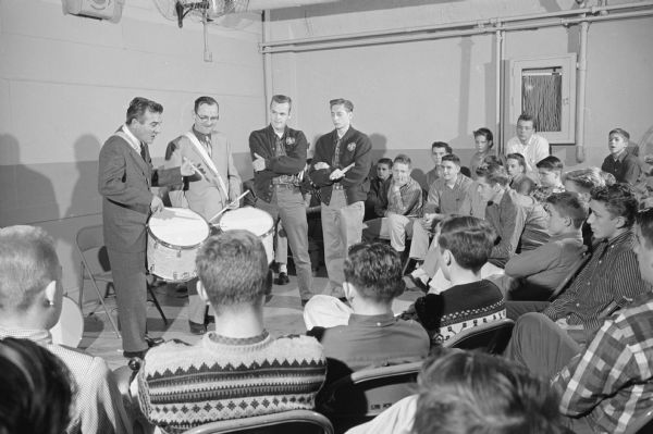 Famous drummer Gene Krupa, shown at far left, gives a drumming demonstration to members of the Madison Scouts Drum and Bugle Corps at the corps' headquarters at the Madison Community Center, 16 E. Doty Street. The group's drum instructor, Henry Johnson, 4013 Mandan Crescent Drive, is shown to the left of Krupa.   