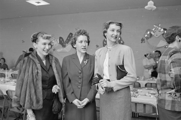 Three guests at the luncheon given by the Democratic women of Dane county to honor the wife of governor-elect Gaylord Nelson, Carrie. Standing are: Pat Cornwell, Mrs. Oswald Anderson, and Margaret Cates.