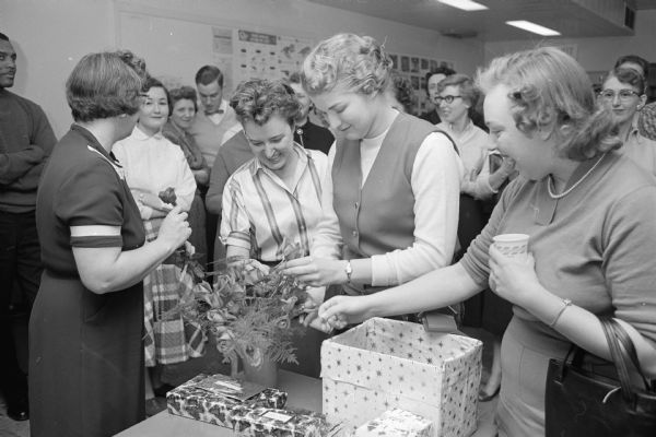 Employee Christmas Party at the City-County Building. A group of women is shown opening Christmas presents. 