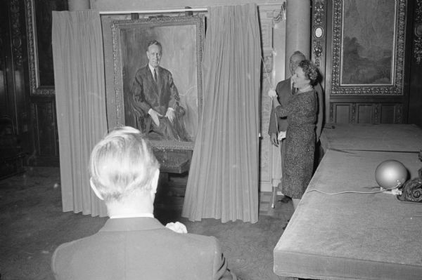 An oil portrait of Governor Vernon Thomson is unveiled by his wife Mrs. Helen Thomson. The portrait will be hung in the State Capitol executive office with portraits of former governors. Shown viewing the portrait in the foreground is Governor Thomson. Behind Mrs. Thomson is LeRoy Luberg, U.W. Dean of Students, who was the master of ceremonies at the event.      