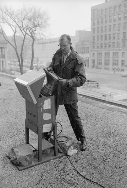 Robert Butler, a public health technologist with the city health department, is examining a used filter. He is atop the second floor of the City-County building standing by an apparatus similar to a home vacuum cleaner that sucks air through a filter. The filter went from white to black in 24 hours.